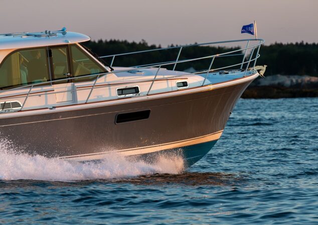 Forward quarter view of the Sabre 43 slicing through chop, bow rail and spray in golden hour