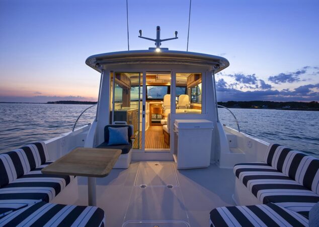 Back Cove 412 cockpit lounge at sunset with striped seating table and warm interior lighting