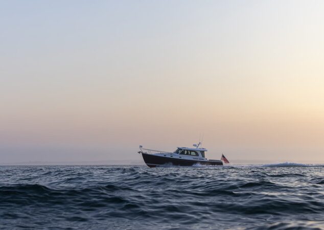 Back Cove 412 cruising offshore at dusk with silhouette against pastel sky