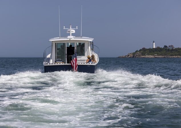 Stern view of Back Cove 412 underway leaving a foamy wake with lighthouse in background