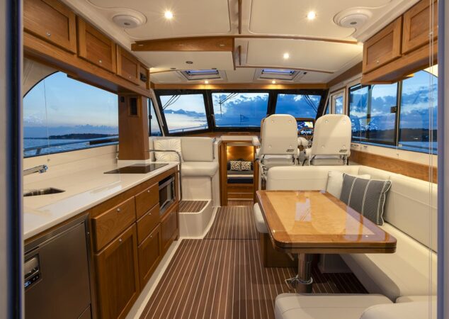 Back Cove 412 galley and salon with wood cabinetry dinette seating and helm chairs at sunset