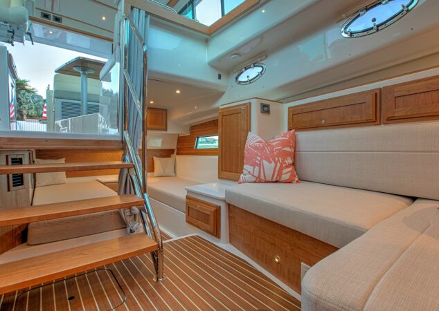Below-deck view of the Back Cove 39O with open staircase, twin settees, wood cabinetry, and striped accent pillows