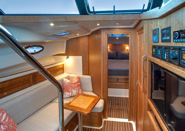 Companionway seating area with striped cushions and wood table aboard the Back Cove 39O, leading to the forward stateroom
