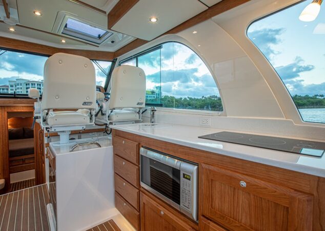 Galley of the Back Cove 39O featuring microwave, induction cooktop, sink, and storage beneath large windows