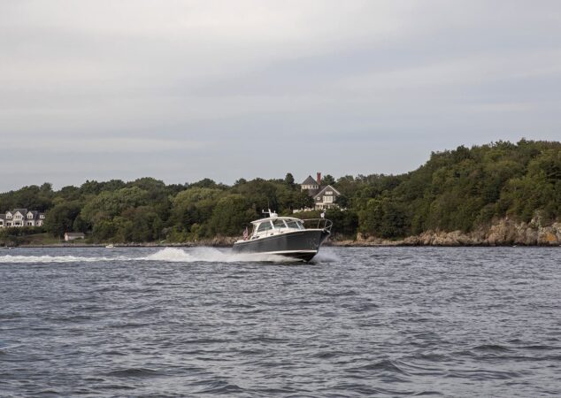 Back Cove 34O running offshore with shoreline homes in background