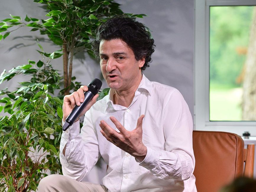 Bertrand Duplat sits on stage, giving a talk at the Boma France Campfire.