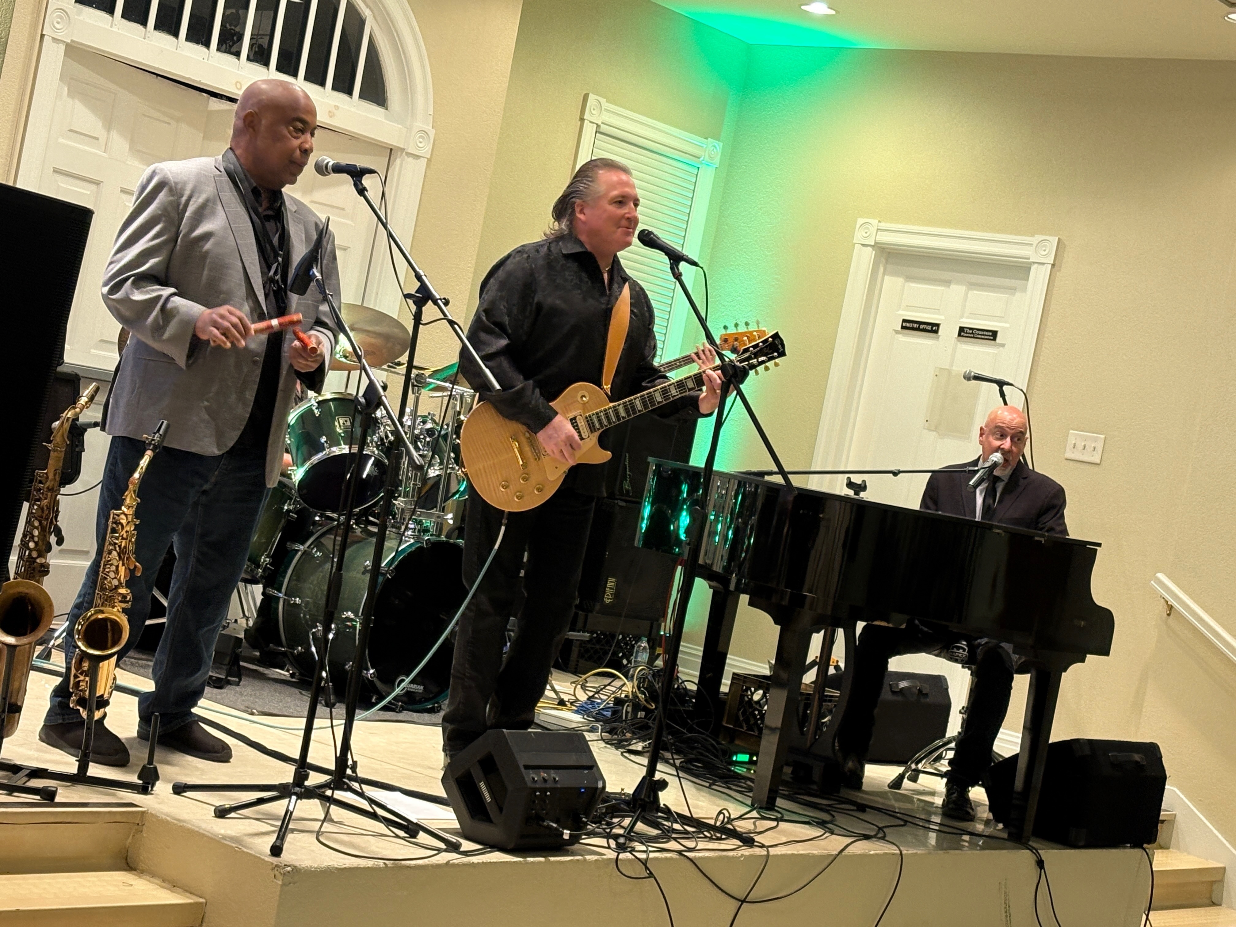 The tribute band performing on stage, with the pianist singing at a grand piano
