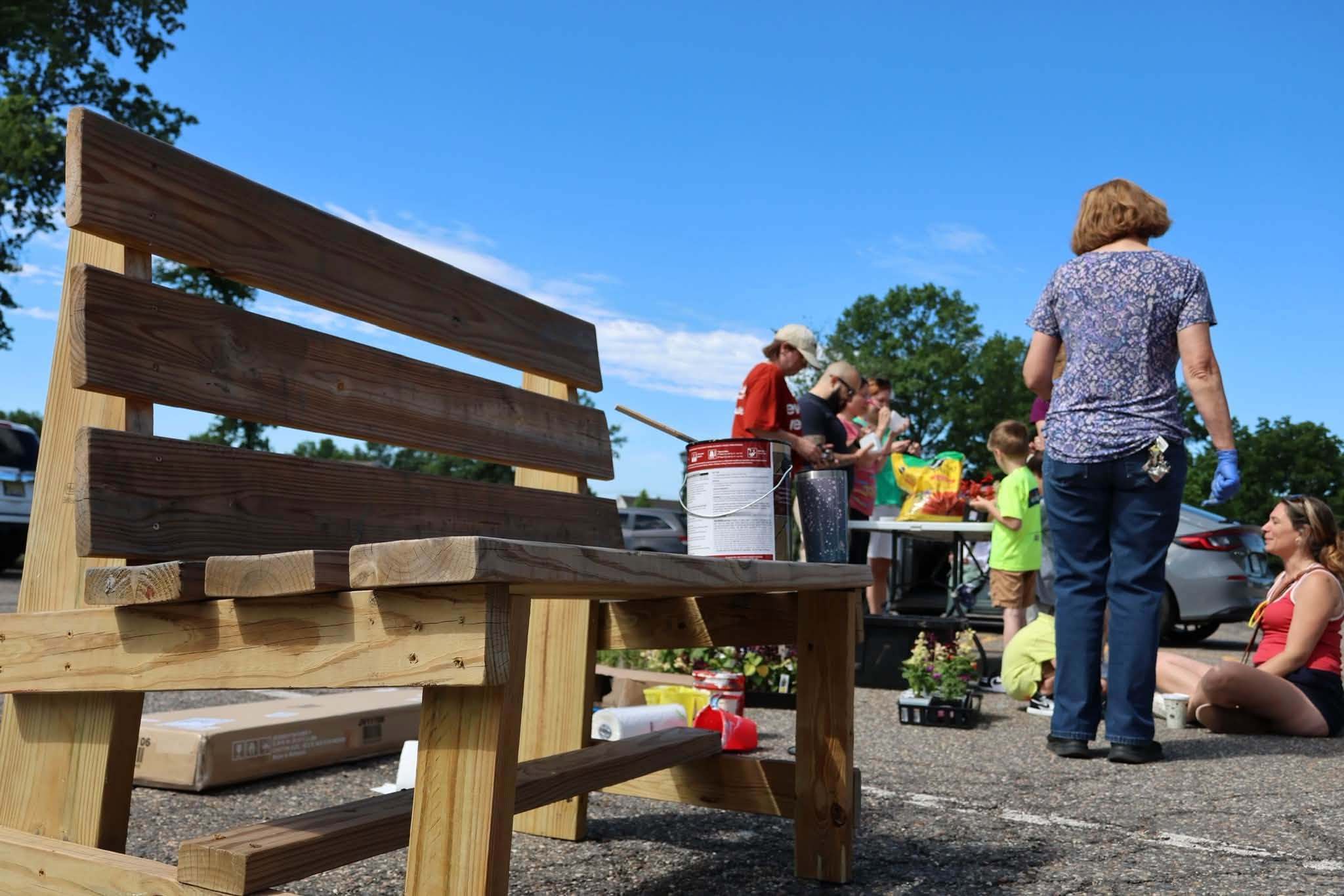A wooden bench being stained in the church parking lot
