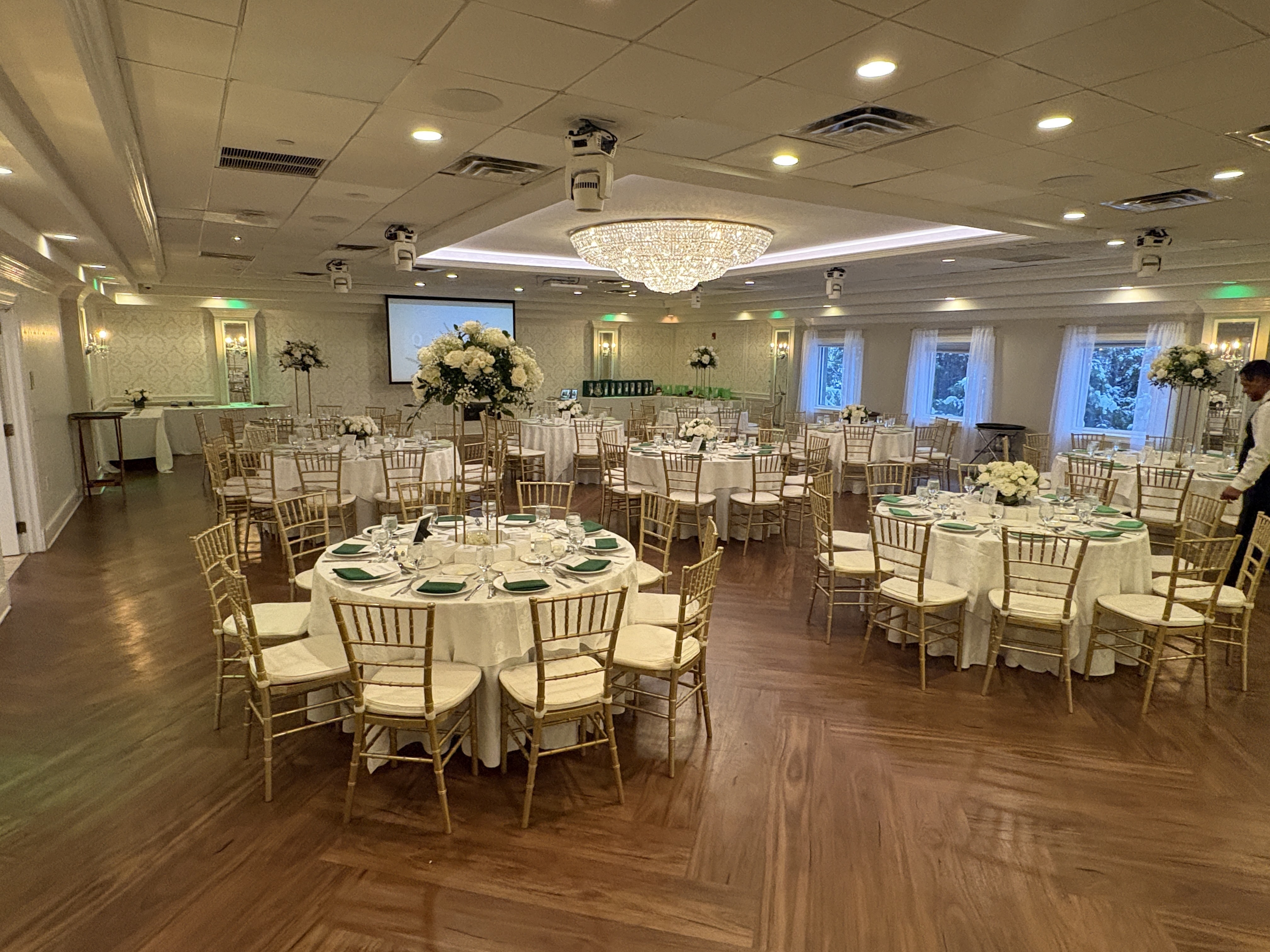 The ballroom at Bridgewater Manor set with white florals and green napkins for the anniversary dinner