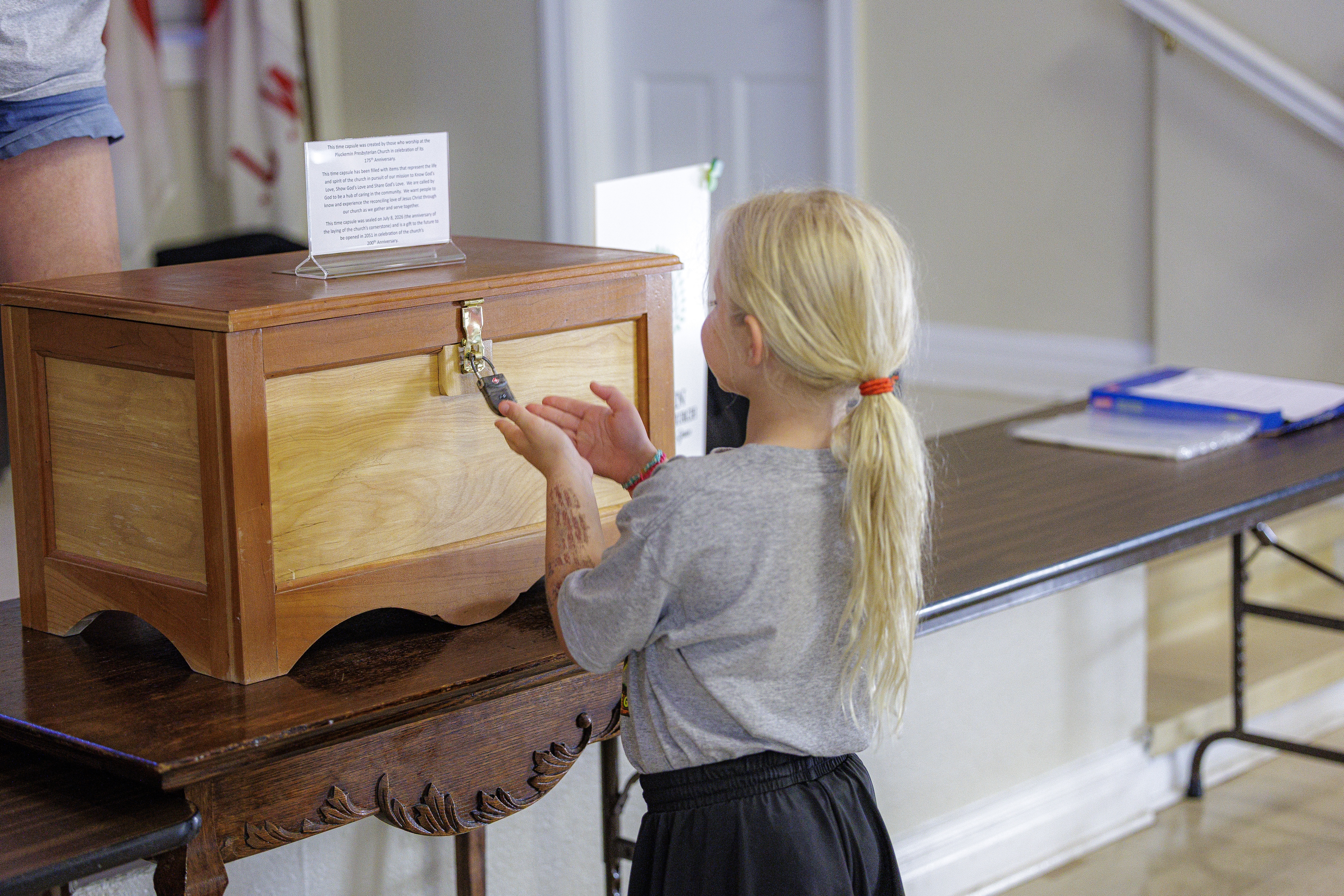 A young girl with her hands on the sealed wooden time capsule