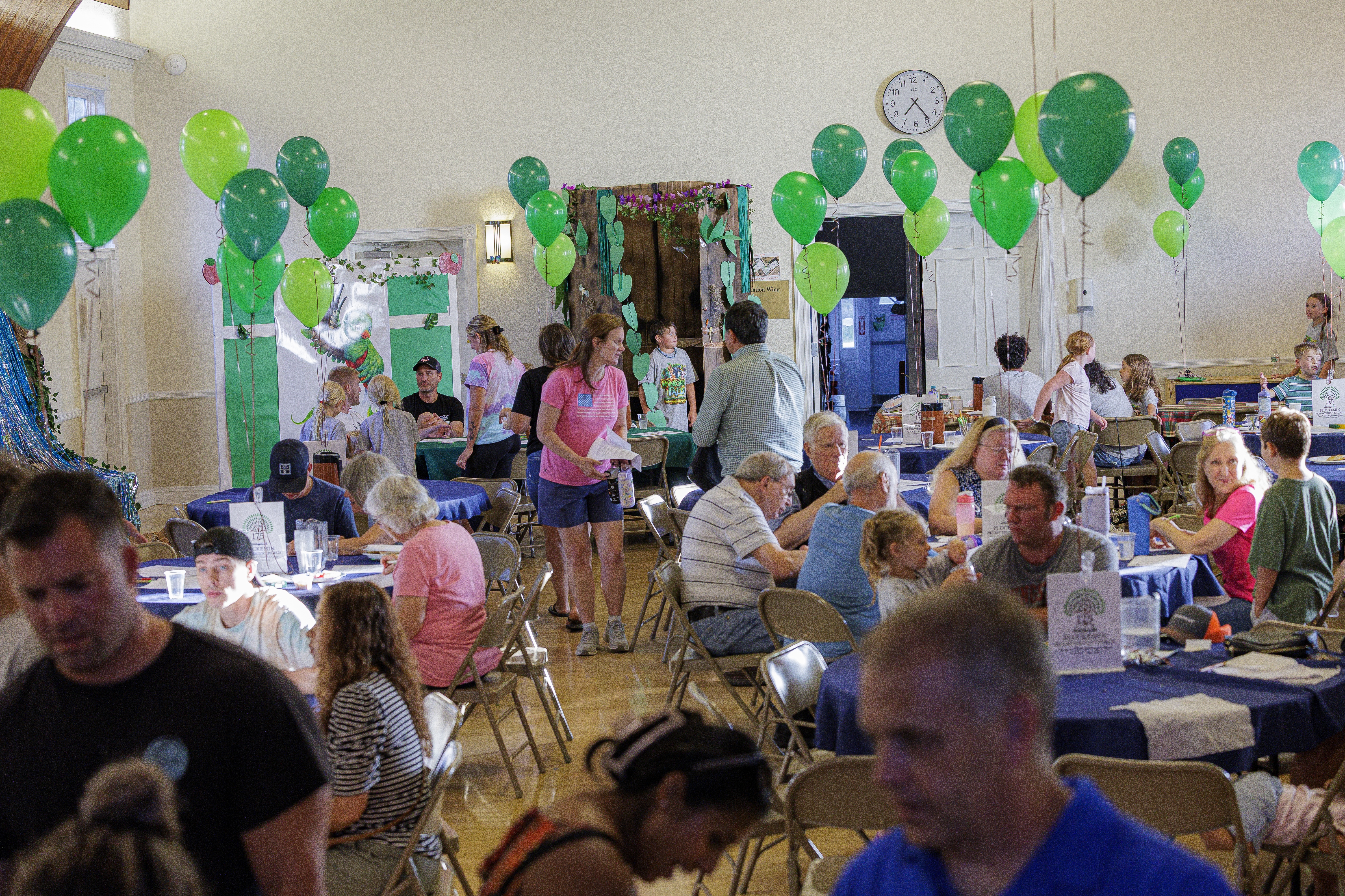 A full Fellowship Hall decorated with green balloons during the time capsule dinner