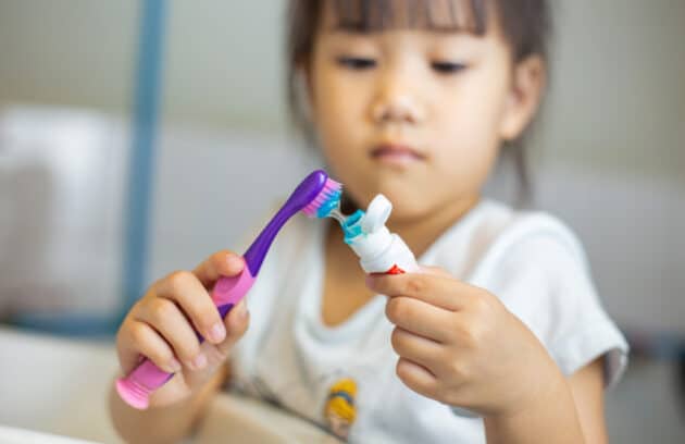 Child Putting Toothpaste on Toothbrush