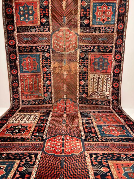 A red carpet with a garden design features water channels, fish, trees, and flowers.