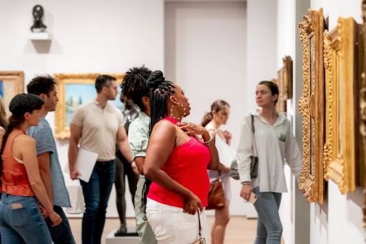 Several museum visitors viewing artworks in a gallery.