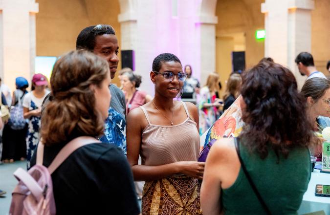 Museum visitors gather in the Calderwood Courtyard at night and engage in covnersation.