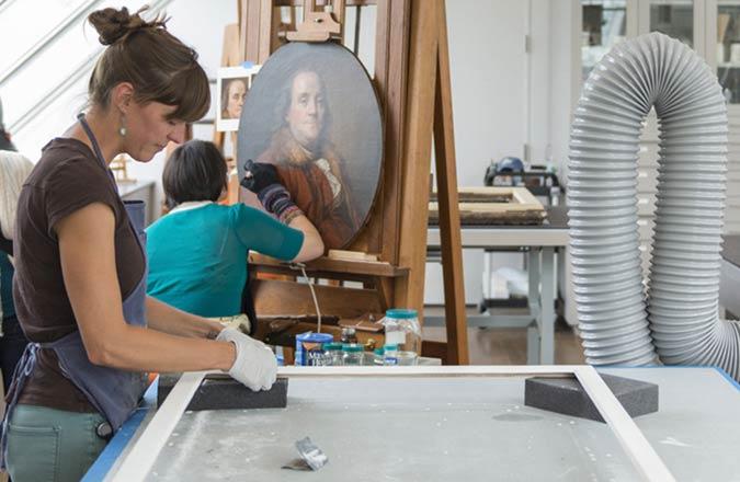 Conservators treat art objects surrounded by technical equipment.
