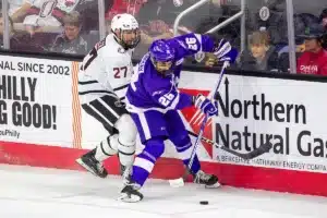 Omaha Mavericks forward Matt Miller (27) fights for the puck against Niagara Purple Eagles defenseman Alex Murray (26) in the first period during a college hockey match on Friday, October 13, 2023, in Omaha, Nebraska. Photo by John S. Peterson.