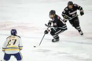 Omaha Maverick forward Ty Mueller (19) skates with the puck against Augustana Viking forward Chase Brand (27) in the second period during the hockey match on Saturday, November 25, 2023, in Lincoln, Neb. Photo by John S. Peterson.