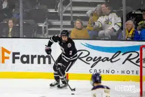 Omaha Maverick defenseman Joaquim Lemay (2) skates with the puck against the Augustana Vikings as a couple does a selfie in the second period during the hockey match on Saturday, November 25, 2023, in Lincoln, Neb. Photo by John S. Peterson.
