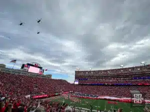 Three Army Guard CH-47 Chinook helicopters from Grand Island flyove as a football sized American flag unfurled for the National Anthem and Veteran's Day celebration before the football game between the Nebraska Cornhuskers and the Maryland Terrapins  on Saturday, November 11, 2023, in Lincoln, Nebraska. Photo by John S. Peterson.