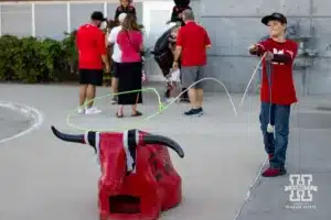 Nebraska Cornhusker fan tries his hand at roping before the match against the Texas A&M CC Islanders during the college volleyball game Friday, August 30, 2024, in Lincoln, Nebraska. Photo John S. Peterson.