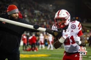 Nebraska Cornhuskers running back Emmett Johnson (21) runs with the ball while running backs coach E.J. Barthel tries to knock out the ball during a college football game against the Iowa Hawkeyes Friday, November 29, 2024, in Iowa City, Iowa. Photo by John S. Peterson.