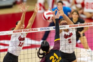 Nebraska Cornhusker Merritt Beason (13) and Rebekah Allick (5) jump up against Minnesota Golden Gopher Alex Acevedo (21) spiking the ball in the third set during a college volleyball match Thursday, November 14, 2024, in Lincoln, Nebraska. Photo by John S. Peterson.