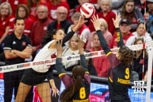Nebraska Cornhusker Harper Murray (27) tips the ball over the net against Minnesota Golden Gopher Calissa Minatee (8) and Lydia Grote (9) during a college volleyball match Thursday, November 14, 2024, in Lincoln, Nebraska. Photo by John S. Peterson.