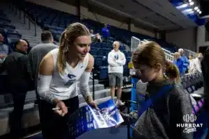 Creighton Bluejay middle blocker Kiara Reinhardt (5) signs an autograph for a young fan after the win over the St. John's Red Storm during a college volleyball match Friday, November 1, 2024, in Omaha, Nebraska. Photo by John S. Peterson.