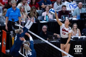 Nebraska Cornhuskers outside hitter Merritt Beason (13) spikes the ball against Penn State Nittany Lions outside hitter Jess Mruzik (9) and Maggie Mendelson during the semi-final round in the NCAA championship Thursday, December 19, 2024, in Louisville, Kentucky. Photo by John S. Peterson.