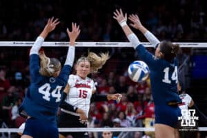 Nebraska Cornhuskers middle blocker Andi Jackson (15) spikes the ball past Penn State Nittany Lions middle blocker Maggie Mendelson (44) and Caroline Jurevicius in the first set during the semi-final round in the NCAA championship Thursday, December 19, 2024, in Louisville, Kentucky. Photo by John S. Peterson.
