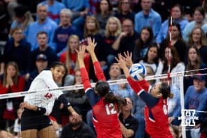 Nebraska Cornhuskers outside hitter Taylor Landfair (12) spikes the ball past Dayton Flyers middle hitter Liana Sarkissian (12) and setter Alyssa Miller (8) in the second set during the first regional match in the NCAA championship Friday, December 13, 2024, in Lincoln, Nebraska. Photo by John S. Peterson.