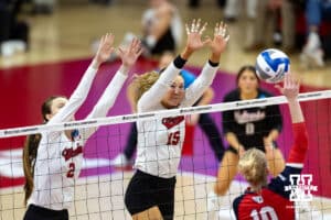 Nebraska Cornhuskers setter Bergen Reilly (2) and Andi Jackson set up to block Dayton Flyers outside hitter Taylor Russell (10) in the second set during the first regional match in the NCAA championship Friday, December 13, 2024, in Lincoln, Nebraska. Photo by John S. Peterson.