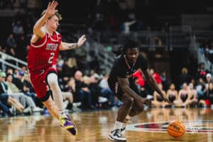Omaha Maverick JJ White crosses up South Dakota player during a basketball game at Baxter Arena on February 22nd, 2025 in Omaha Nebraska. Photo by Collin Stilen.