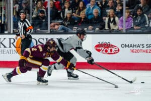 Omaha Maverick Myles Hilman and Minnesota player battling for the puck during a hockey match at Baxter Arena on Saturday, February 2, 2025, in Omaha, Nebraska. Photo by Collin Stilen.
