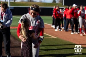 Nebraska Cornhusker starting pitcher Jordyn Bahl (98) gives the little that sang the National Anthem a hug before taking on the Minnesota Golden Gophers during a college softball game Friday, March 21, 2025 in Lincoln, Nebraska. Photo by John S. Peterson.