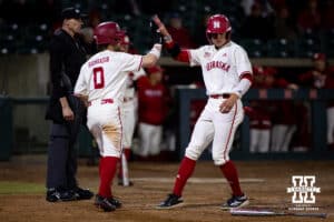 Nebraska Cornhusker Case Sanderson (14), right, scores on a wild pitch getting a high five from Cayden Brumbaugh (0) in the eighth against the Wichita St. Shockers during a college baseball game Tuesday, March 11, 2025 in Lincoln, Nebraska. Photo by John S. Peterson.