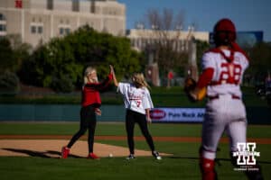 In memory of Greg Sharpe, daughters Emily Bowen and Taylor Sharpe give each other a high five after throwing out the first pitch before Nebraska takes on Kansas State during a college baseball game Tuesday, April 29, 2025 in Lincoln, Nebraska. Photo by John S. Peterson.