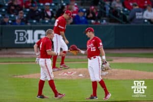 Nebraska Cornhusker infielder Dylan Carey (15) hands Josh Overbeek his hat and glove during a college baseball game Tuesday, April 22, 2025 in Lincoln, Nebraska. Photo by John S. Peterson.