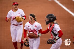 Nebraska Cornhuskers Bella Bacon, Jordyn Bahl (98) and Ava Bredwell (24) head to the dugout against the Indiana Hoosiers during a college softball game Friday, April 18, 2025 in Omaha, Nebraska. Photo by John S. Peterson.