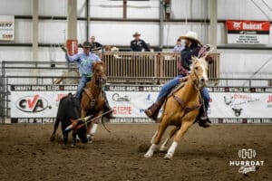 Taylor Cook the header looks back as Jon Pudwill the healer goes to rope the legs of the steer during the John Cook Roping Classic on Sunday, April 13, 2025 in Lincoln, Nebraska. Photo by John S. Peterson.