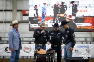 Travis Schauda the announcer describing the saddle presented by Greg Olson, in the blue jacket, Owner of Vitalix Inc to John Cook during the John Cook Roping Classic on Sunday, April 13, 2025 in Lincoln, Nebraska. Photo by John S. Peterson.