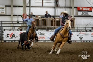 Taylor Cook the header looks back as Jon Pudwill the healer goes to rope the legs of the steer during the John Cook Roping Classic on Sunday, April 13, 2025 in Lincoln, Nebraska. Photo by John S. Peterson.