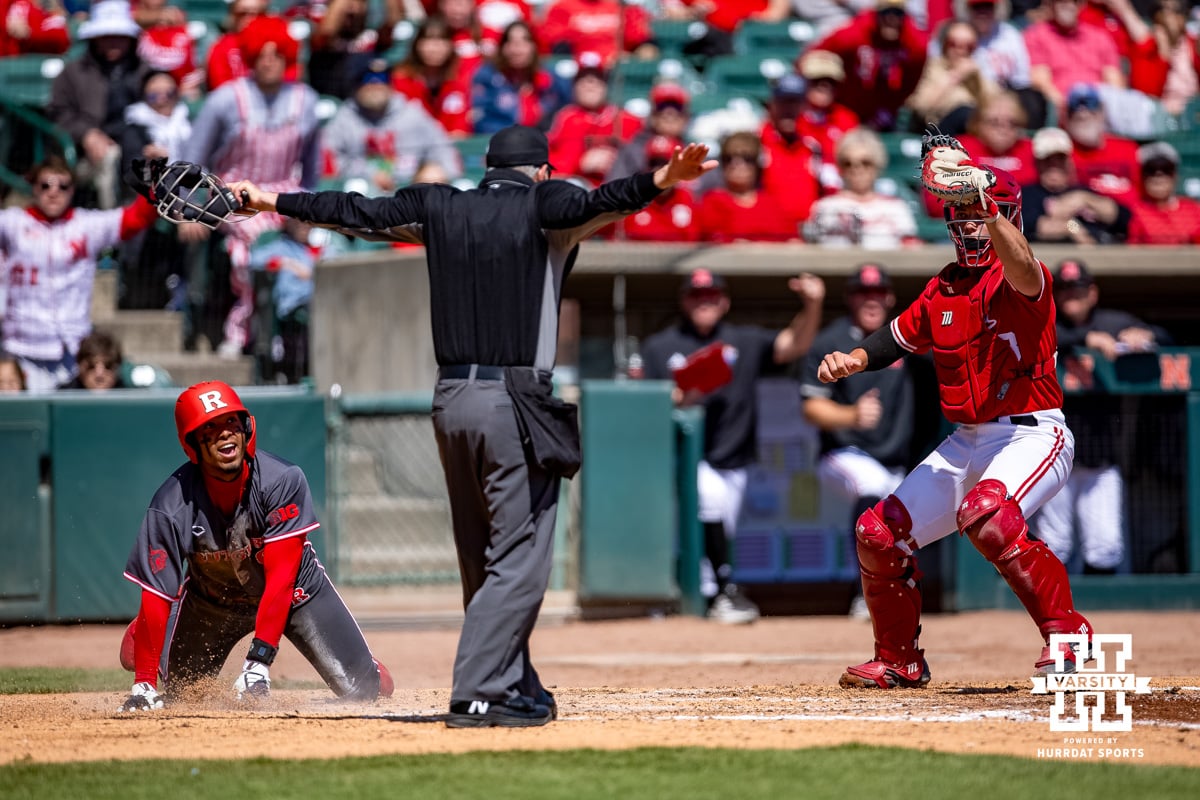 Umpire calls Rutgers Scarlet Knight Pablo Santos (6) safe scoring a run against Nebraska Cornhusker catcher Will Jesske (13) in the fifith inning during a college baseball game Sunday, April 6, 2025 in Lincoln, Nebraska. Photo by John S. Peterson.