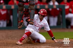 Oregon State Beaver catcher Wilson Weber (18) jumps for the ball as Nebraska Cornhusker infielder Dylan Carey (15) slides home in the seventh during a college baseball game Saturday, March 29, 2025 in Lincoln, Nebraska. Photo by John S. Peterson.