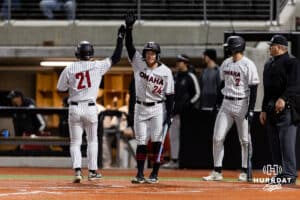 Omaha Maverick utility Sam Beck (21) and Drew Borner scores in the fifth inning against the Nebraska Cornhuskers during a college baseball game Wednesday, April 2, 2025 in Omaha, Nebraska. Photo by John S. Peterson.
