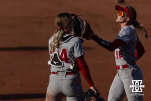 Nebraska Cornhusker Jordyn Bahl (98) gives Ava Bredwell give a glove bump heading to the dugout against the Purdue Boilermakers during a college softball game Monday, March 31, 2025 in Lincoln, Nebraska. Photo by John S. Peterson.