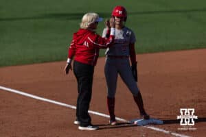 Nebraska Cornhusker Hannah Camenzind (9) gets a high five from head coach Rhonda Revelle in the third inning during a college softball game Monday, March 31, 2025 in Lincoln, Nebraska. Photo by John S. Peterson.
