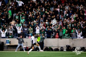 Schuyler Defender Richard Delgado (22) celebrates with the Schuyler crowd after a critical goal in the second half during the NSAA Boys Class B soccer finals on Tuesday, May 20, 2025, in Omaha, Nebraska. Photo by Braden Cochran.