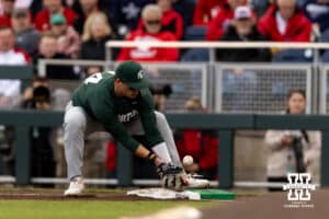 Michigan State Spartan first baseman Sam Busch (24) misses the ball bouncing off the base on a hit from Nebraska Cornhusker Cayden Brumbaugh (0) during the Big Ten Baseball Tournament on Tuesday, May 20, 2025 in Omaha, Nebraska. Photo by John S. Peterson.